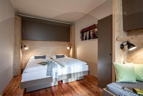 sypialnia z łóżkiem z białymi prześcieradłami i drewnianą podłogą w obiekcie JUFA Hotel Maria Lankowitz w mieście Maria Lankowitz