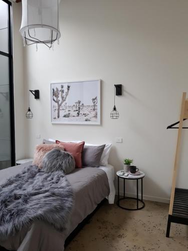 a bedroom with a bed with a blanket and a table at THE WAREHOUSE APARTMENTS in Geelong