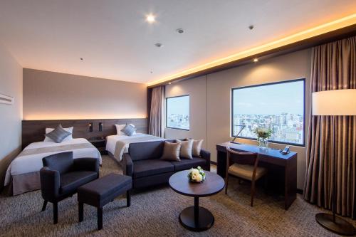 川崎市にある川崎日航ホテルのベッド2台とソファが備わるホテルルームです。