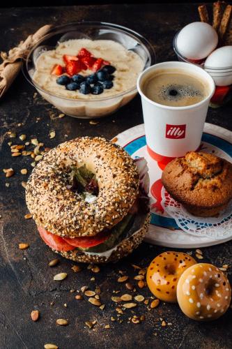 une table avec un bagel, une tasse de café et une assiette de nourriture dans l'établissement Vip Rotermanni Apartment, à Tallinn