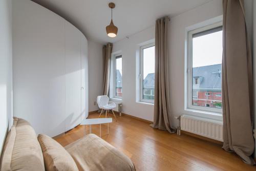 a living room with a couch and two windows at Studio des jardins suspendus in Liège