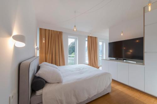 a bedroom with a white bed and a television at Studio des jardins suspendus in Liège