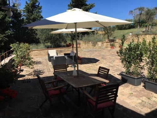 a wooden table with an umbrella and chairs at Case Nell' Aia in Poggibonsi