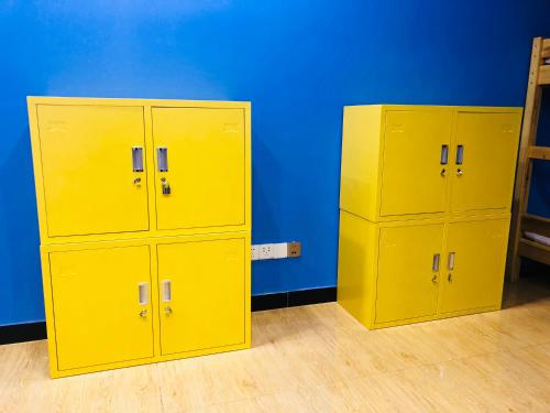 two yellow lockers in a room with a blue wall at Lemongo Youth Hostel Hohhot in Hohhot
