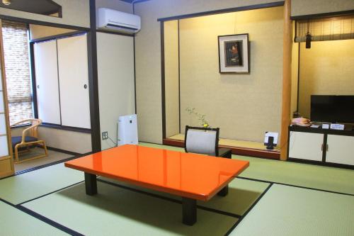 a living room with an orange table in a room at Kanazawa Chaya in Kanazawa