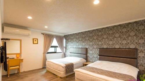 a hotel room with two beds and a desk at Yilan Jimmy Villa in Yilan City