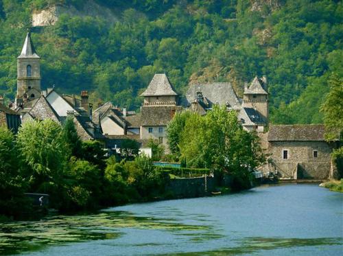 a group of buildings with a river and a church at L'Ancienne Ecole in Entraygues-sur-Truyère