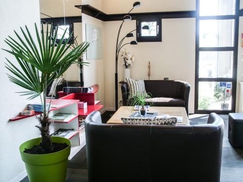 a living room with a couch and a potted plant at Hôtel Inn Design Resto Novo Chartres in Chartres