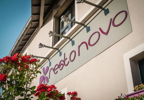 a sign on the side of a building with flowers at Hôtel Inn Design Resto Novo Chartres in Chartres