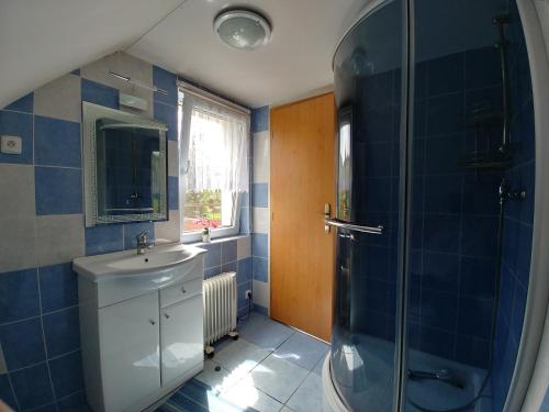 y baño de azulejos azules con lavabo y ducha. en Podkroví - ubytování Brdy, en Bohutín