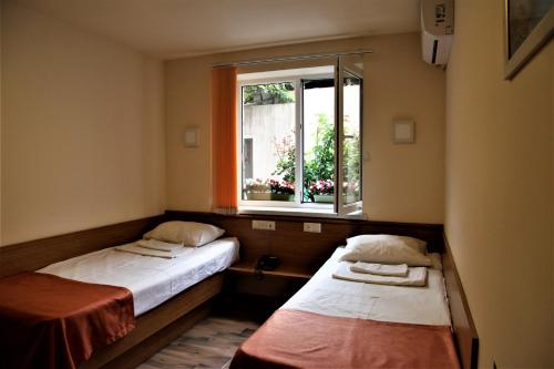 two beds in a room with a window at Albert House Hotel and Tours in Yerevan