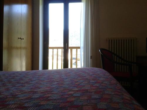 a bedroom with a bed and a large window at Hotel Serenella in Canale San Bovo