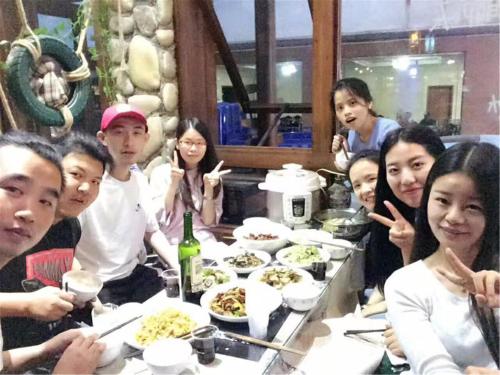 a group of people sitting at a table with food at Zhangjiajie Highlights Guesthouse in Zhangjiajie
