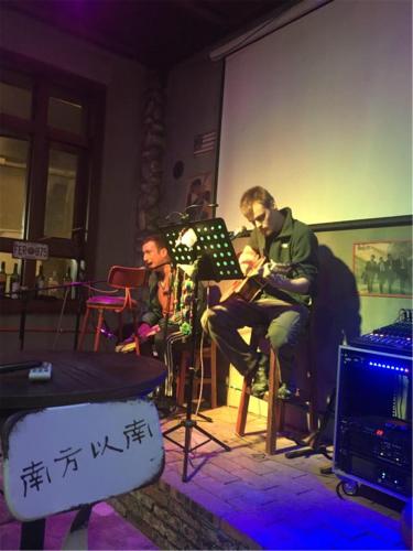 two men are sitting in a room with a table at Zhangjiajie Highlights Guesthouse in Zhangjiajie