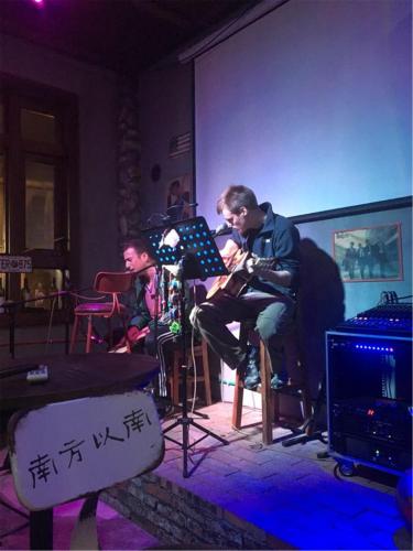 a man sitting in a room playing a guitar at Zhangjiajie Highlights Guesthouse in Zhangjiajie