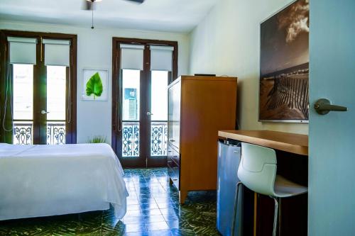 a hotel room with a bed and a desk and windows at Navona Studios in San Juan