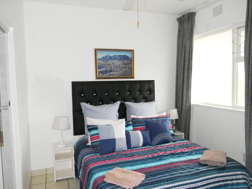 a bedroom with a large bed with colorful pillows at Dumela Margate Flat No 14 in Margate