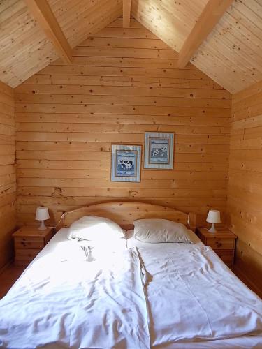 a bed in a wooden room with two lamps at Himmelpfort Ferienhäuser am Eichberg in Fürstenberg