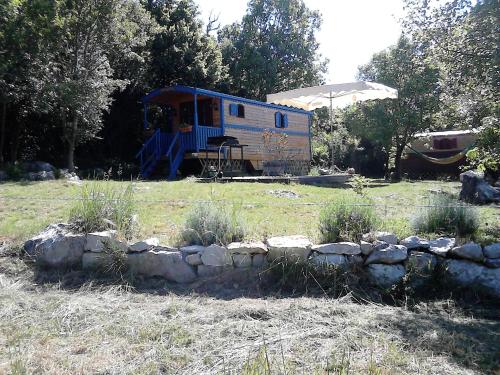 an old truck parked in a field with a stone wall at Roulotte-Quinta La Grange d Emile in Blandas