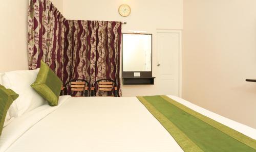 a bedroom with a bed and a window and a mirror at Treebo Light House, 900 Mtrs From Botanical Garden in Ooty