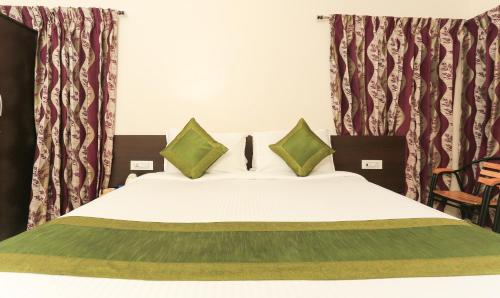 a bed with green and white sheets and pillows at Treebo Light House, 900 Mtrs From Botanical Garden in Ooty