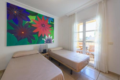 アデへにあるRelax El Duqueの壁に絵画が飾られた部屋のベッド2台