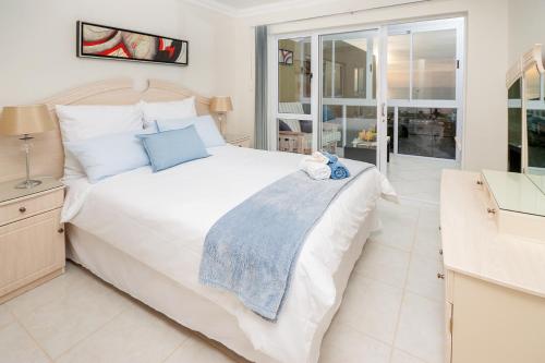 a bedroom with a large white bed and a balcony at Main Beach Penthouse in Jeffreys Bay