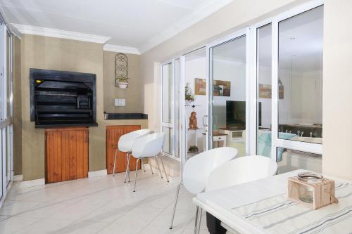sala de estar con sillas blancas y chimenea en Main Beach Penthouse, en Jeffreys Bay