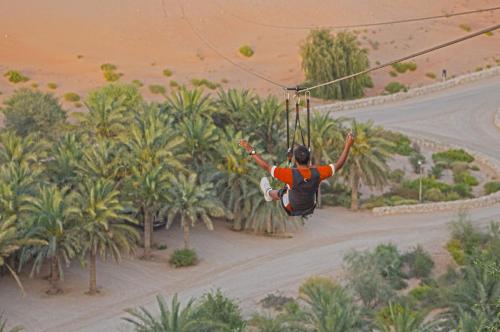 a woman on a zip line in the desert at Telal Resort Al Ain in Al Ain