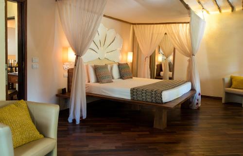 een slaapkamer met een bed met gordijnen en een bank bij Essque Zalu Zanzibar in Nungwi