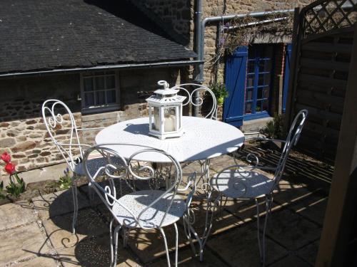 une table blanche et des chaises avec une lanterne dessus dans l'établissement Au Bon Accueil, à Saint-Marcan