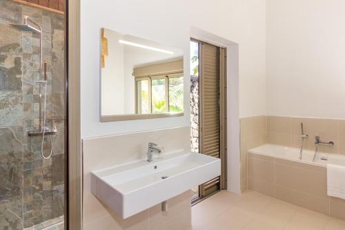 un bagno con un lavandino, una vasca e uno specchio di Escale Chic ! Villa de charme au cœur du village balnéaire de Saint-Gilles a Saint-Gilles-les Bains