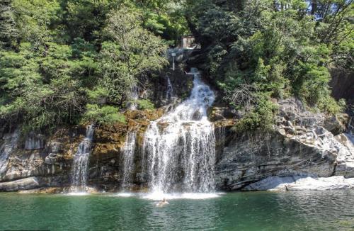 a person swimming in a pond in front of a waterfall at Hotel Al Fiume in Tegna