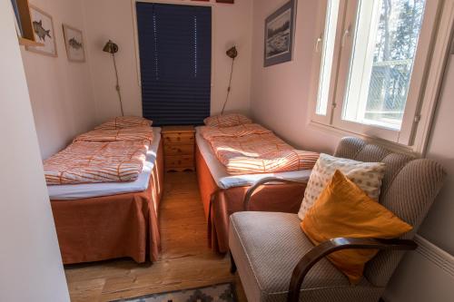 three beds in a room with a chair and a window at Villa Björn with Sauna in Hitis