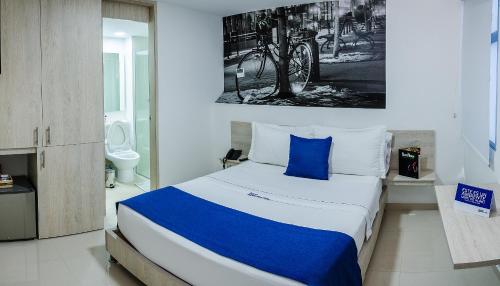 a bedroom with a large bed with a blue pillow at Hotel Laureles Plaza in Medellín