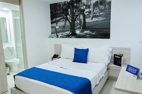 a bedroom with a bed with a blue pillow at Hotel Laureles Plaza in Medellín