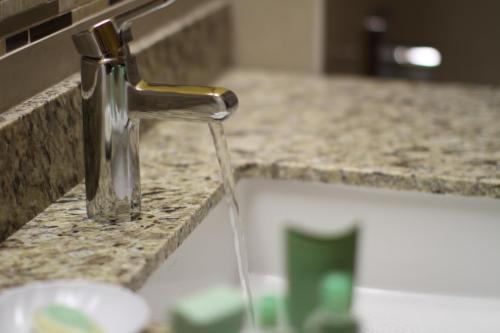 een gootsteen met water uit een kraan bij Marble Waters Hotel & Suites, Trademark by Wyndham in Jacksonville