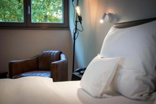 a bedroom with a bed and a chair and a window at Kochs Stadthotel in Olpe