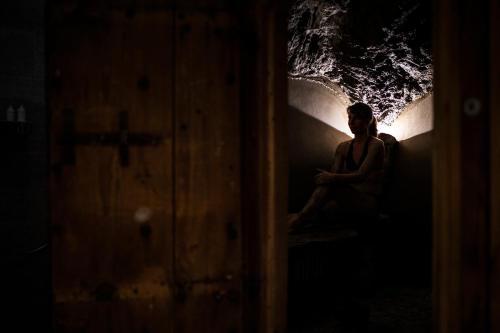 a woman sitting in a dark room with a light at La Bouitte - Hôtel Relais & Châteaux in Saint-Martin-de-Belleville