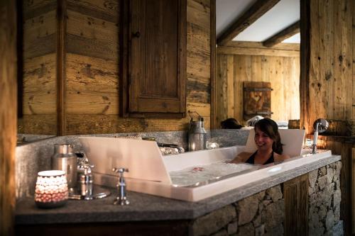 a woman in a bath tub with a laptop at La Bouitte - Hôtel Relais & Châteaux in Saint-Martin-de-Belleville