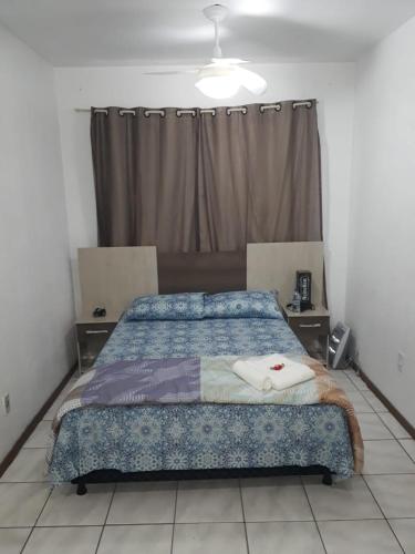a bedroom with a bed with a blue comforter at Apto Jk em Cachoeirinha in Cachoeirinha