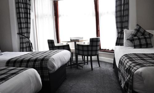 
a hotel room with two beds and two tables at Argyll Guest House in Glasgow
