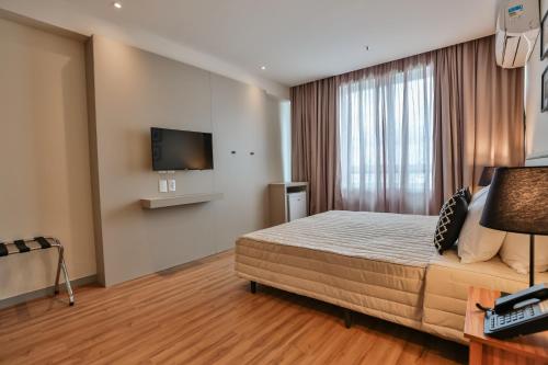 a bedroom with a bed and a flat screen tv at Transamerica Executive Campos dos Goytacazes in Campos dos Goytacazes