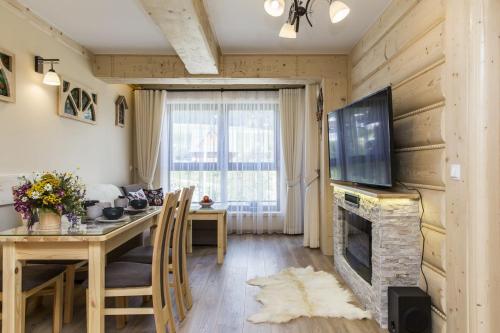 a living room with a dining table and a fireplace at Polana Szymoszkowa Ski Resort in Zakopane