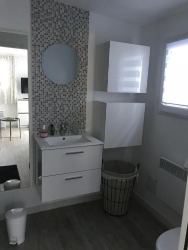 une salle de bain blanche avec un lavabo et un miroir dans l'établissement Les fleurs, à Cannes