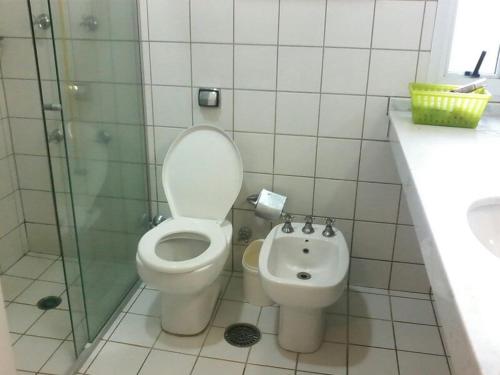 a bathroom with a toilet and a glass shower at Casa em condomínio fechado de frente para o mar e ao lado do rio in Praia Guaratuba