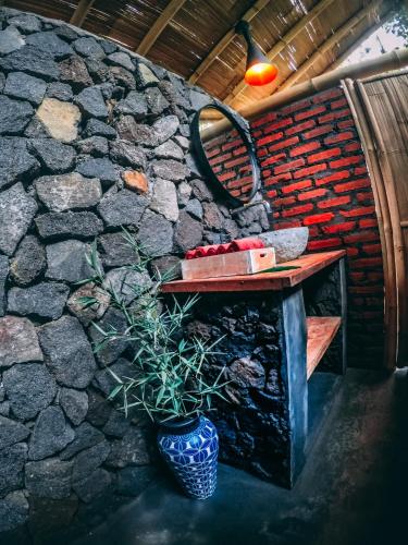 a stone wall with a table and a vase with a plant at Desa Eko in Munduk