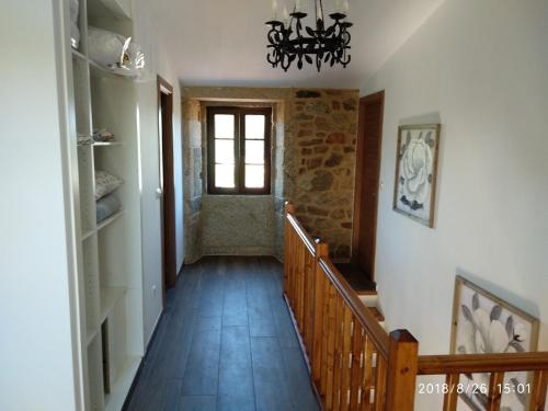 a hallway with a staircase with a window and a chandelier at A Casiña de Esther in Teo