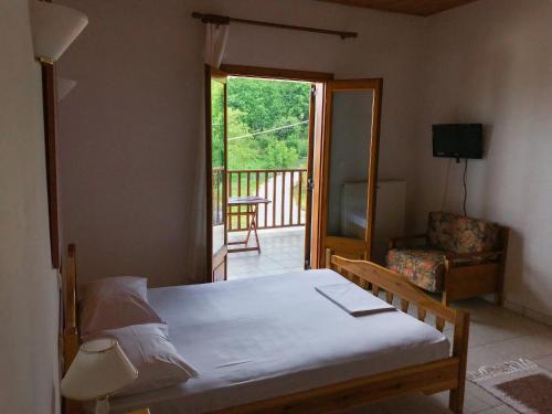a bedroom with a bed and a chair and a balcony at Hotel Antigoni in Neochori