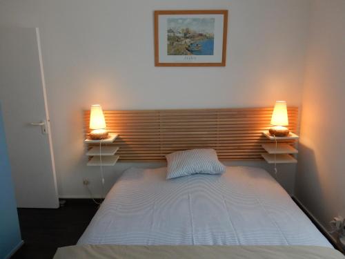 una camera da letto con un letto con due luci sopra di Appartement a dinard a Dinard